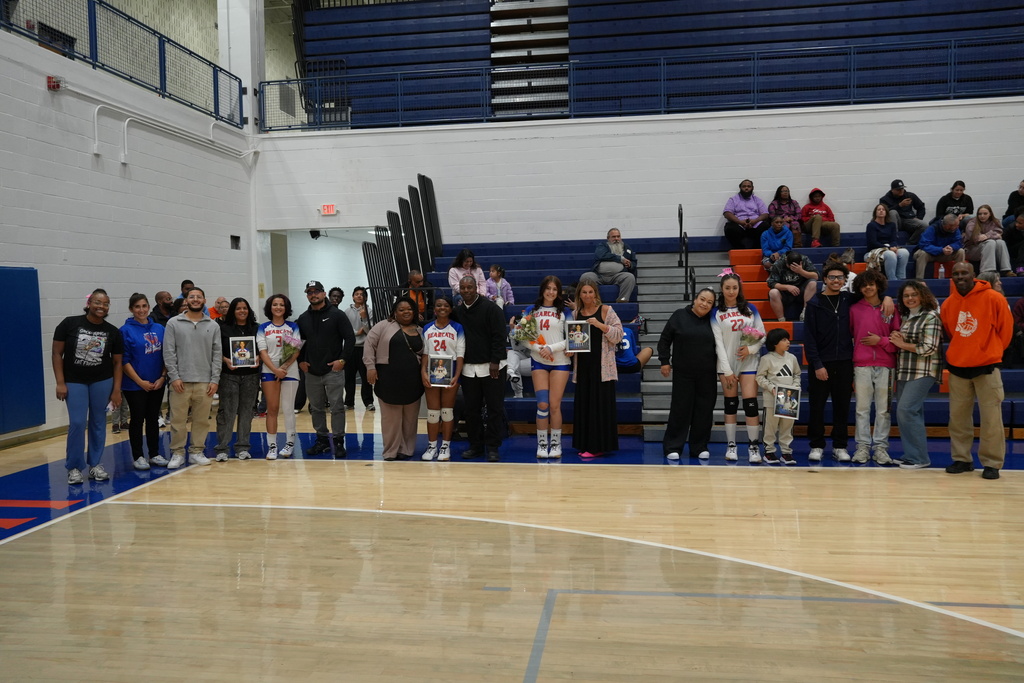 Bearcats volleyball seniors are posing with their families and coaches for group photos during Senior Night in the school gymnasium.