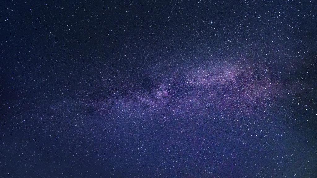 Milky Way stretches across a dark sky with numerous stars. The atmosphere appears calm with a few streaks of light.