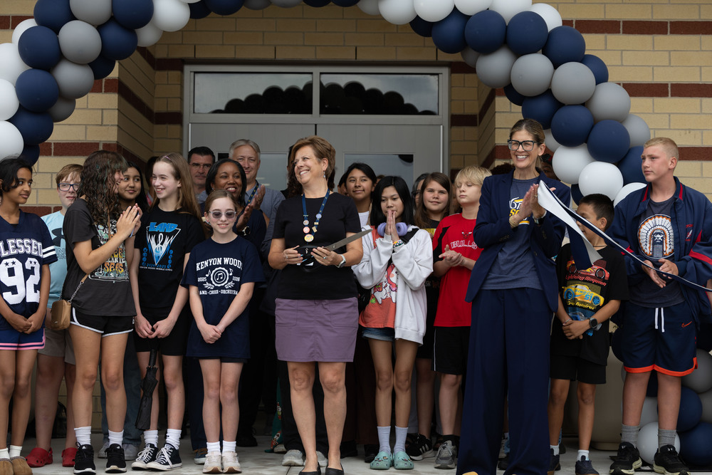 A group of people celebrate as a ribbon is cut