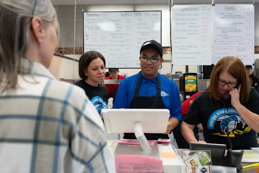 Four people standing around a cash register in a Diner