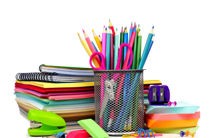 A table with various office supplies including a pencil holder, scissors, colored pencils, a stapler, sticky notes, and notebooks.