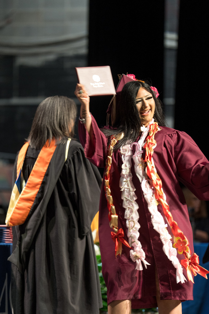 A high school student holds up a diploma