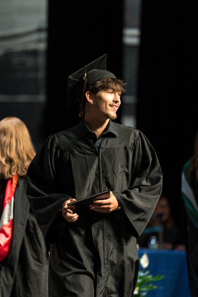 A student smiles as he recieves his diploma