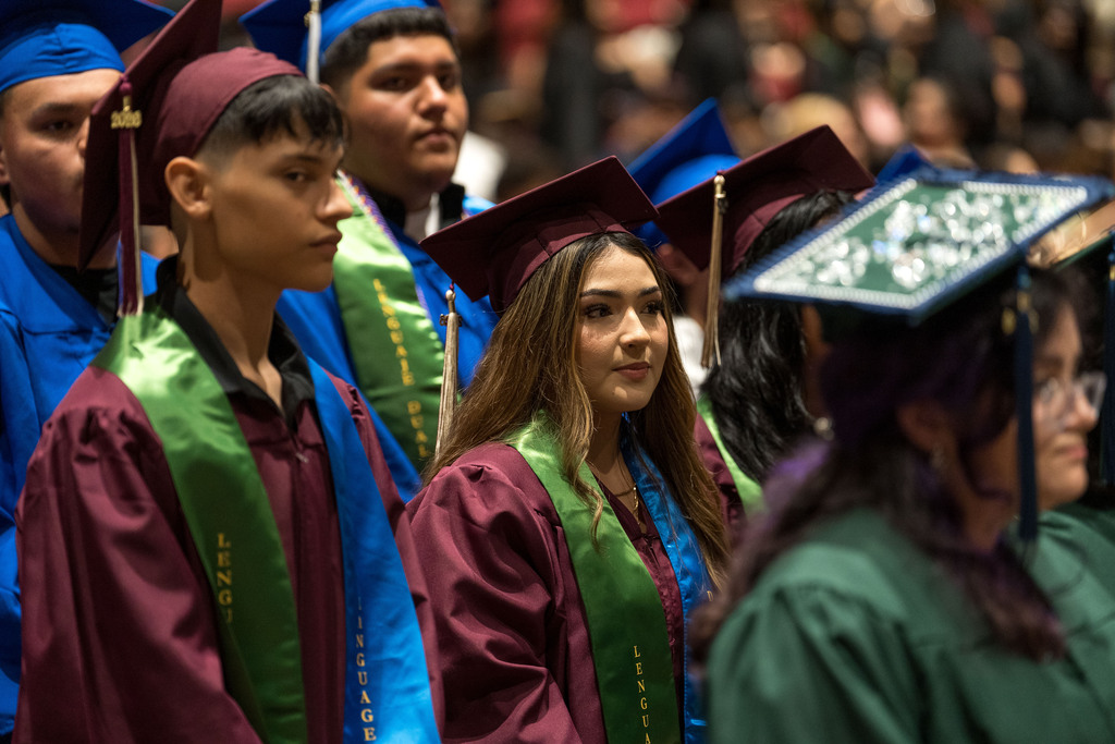 A high school student stands in cap and gown at graduation