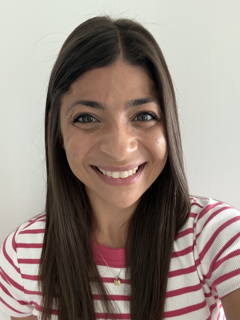 Woman with brown hair, wearing a red and white striped shirt, smiling at the camera.