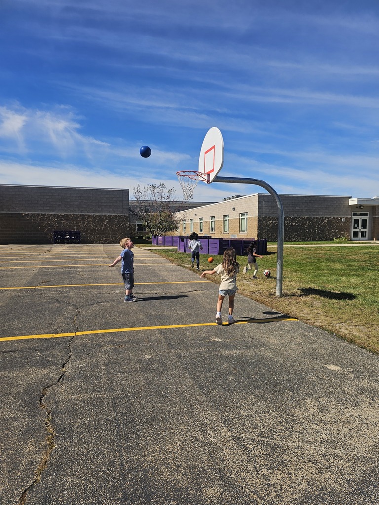 Kindergarten students shooting hoops outside.