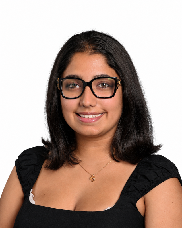 A young woman in glasses smiles at the camera in a portrait syle picture