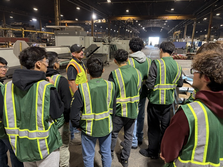 Students being led by High School soccer coach Ulises Fuentes through the Behlens Manufacturing facility.