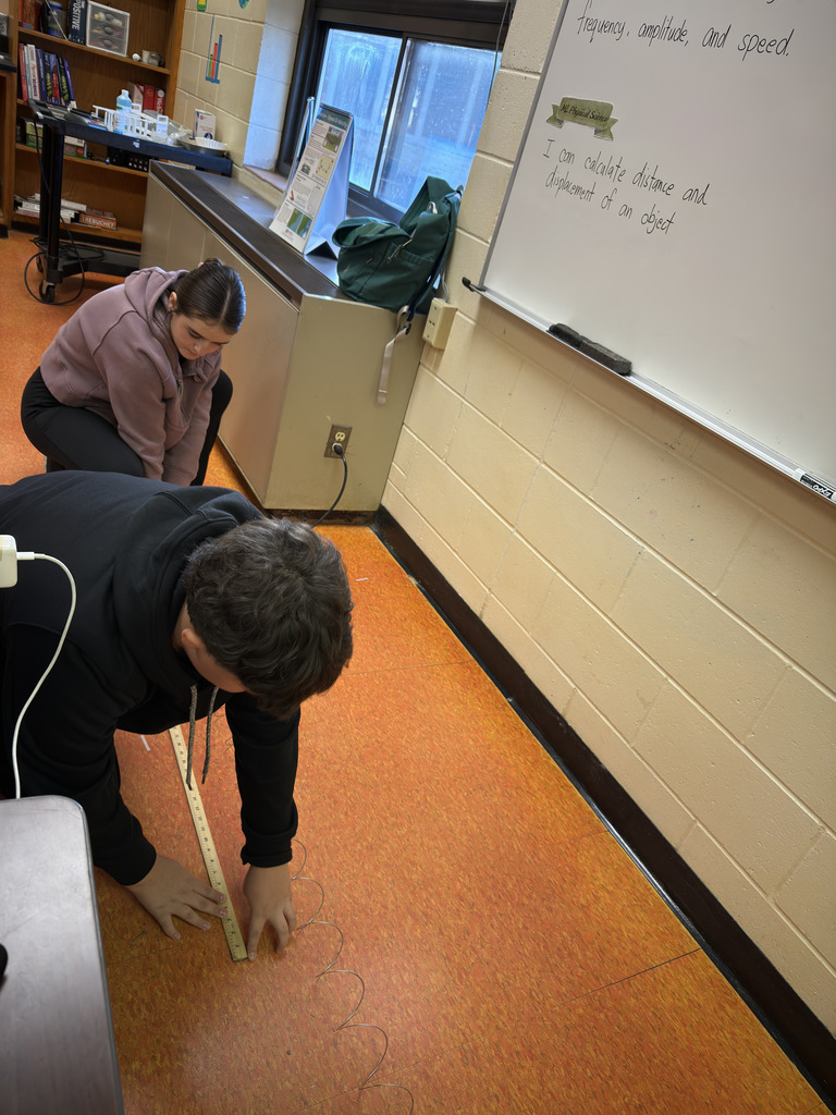 Students in Mrs. Ramos’ class use slinkies to explore waves, stretching and observing them while the teacher guides the hands-on experiment.