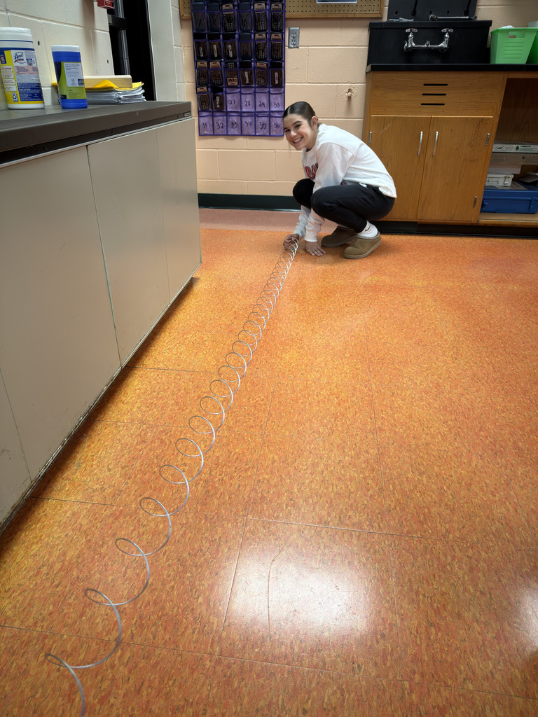 Students in Mrs. Ramos’ class use slinkies to explore waves, stretching and observing them while the teacher guides the hands-on experiment.