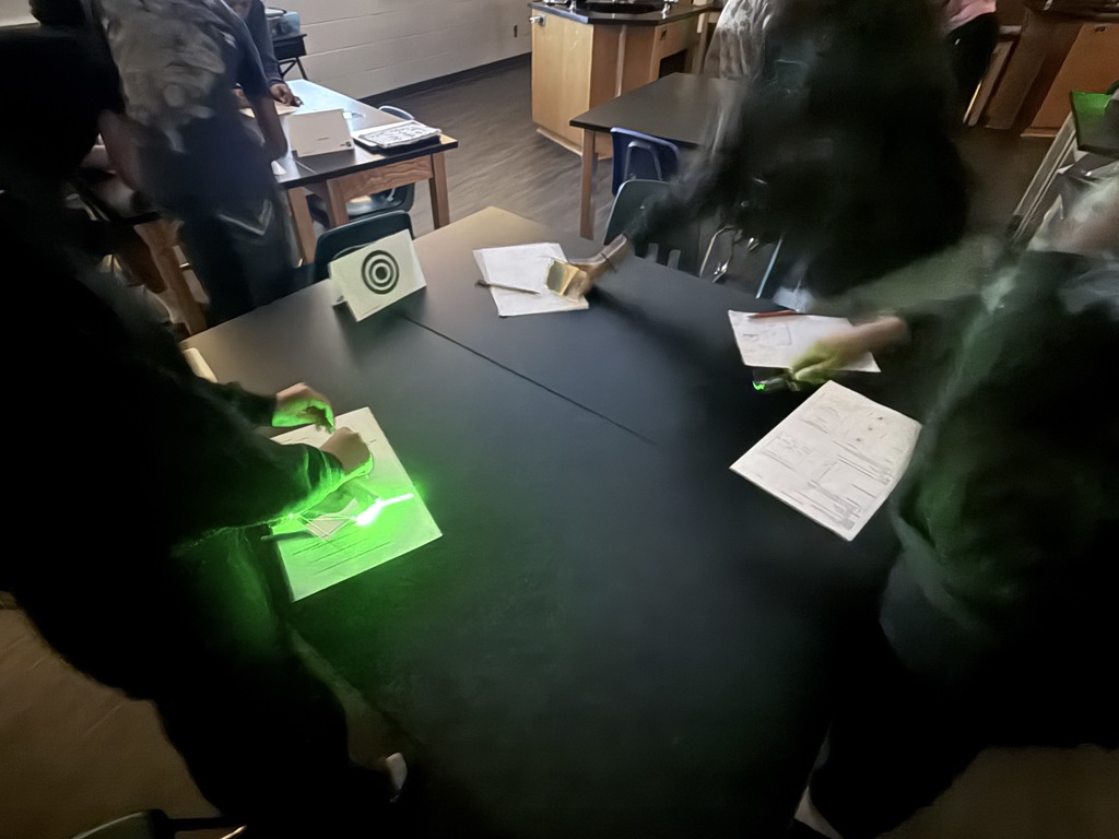 Students in action exploring the properties of light using laser pointers and mirrors.  Discovering how light reflects and changes direction through hands-on learning!