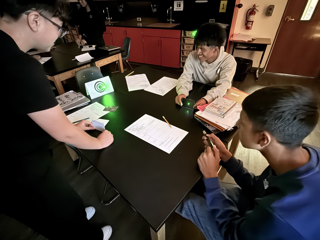 Students in action exploring the properties of light using laser pointers and mirrors.  Discovering how light reflects and changes direction through hands-on learning!