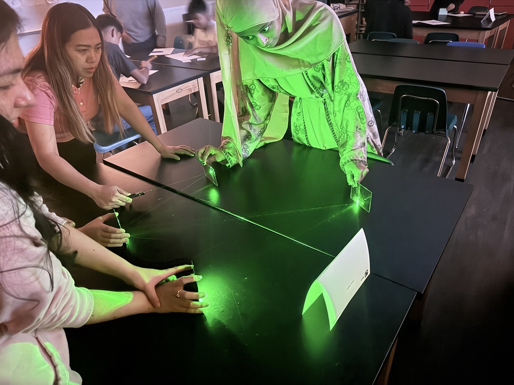 Students in action exploring the properties of light using laser pointers and mirrors.  Discovering how light reflects and changes direction through hands-on learning!