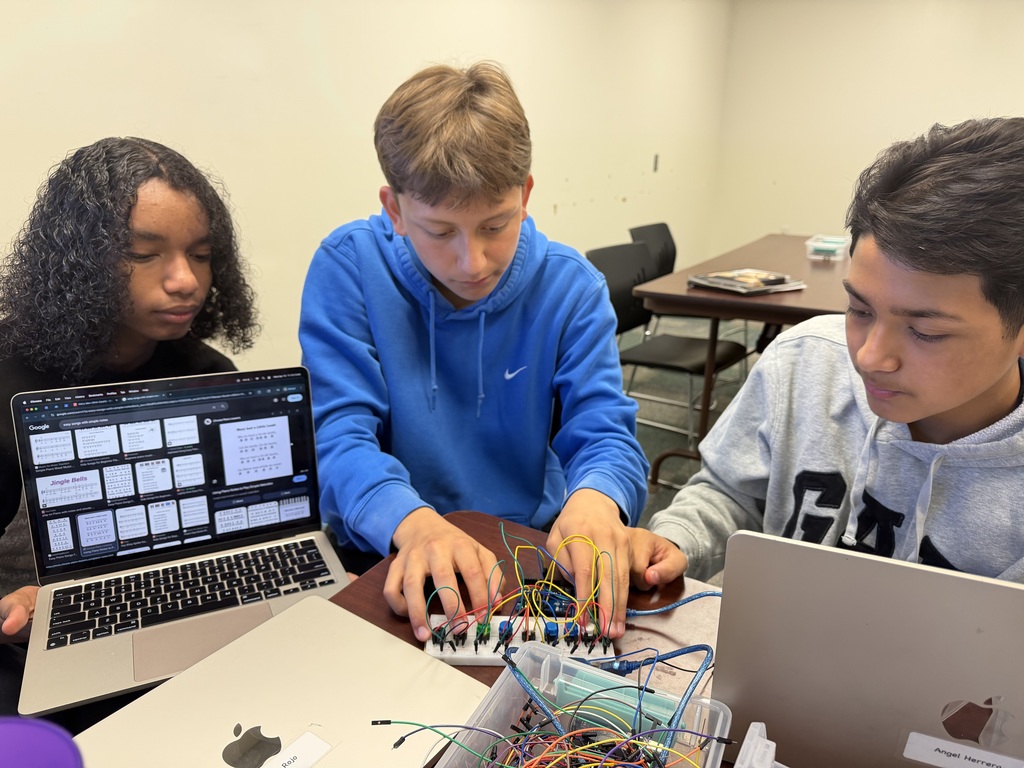 Three students collaborate on a hands-on coding and electronics project, combining creativity, teamwork, and technology to bring their ideas to life.