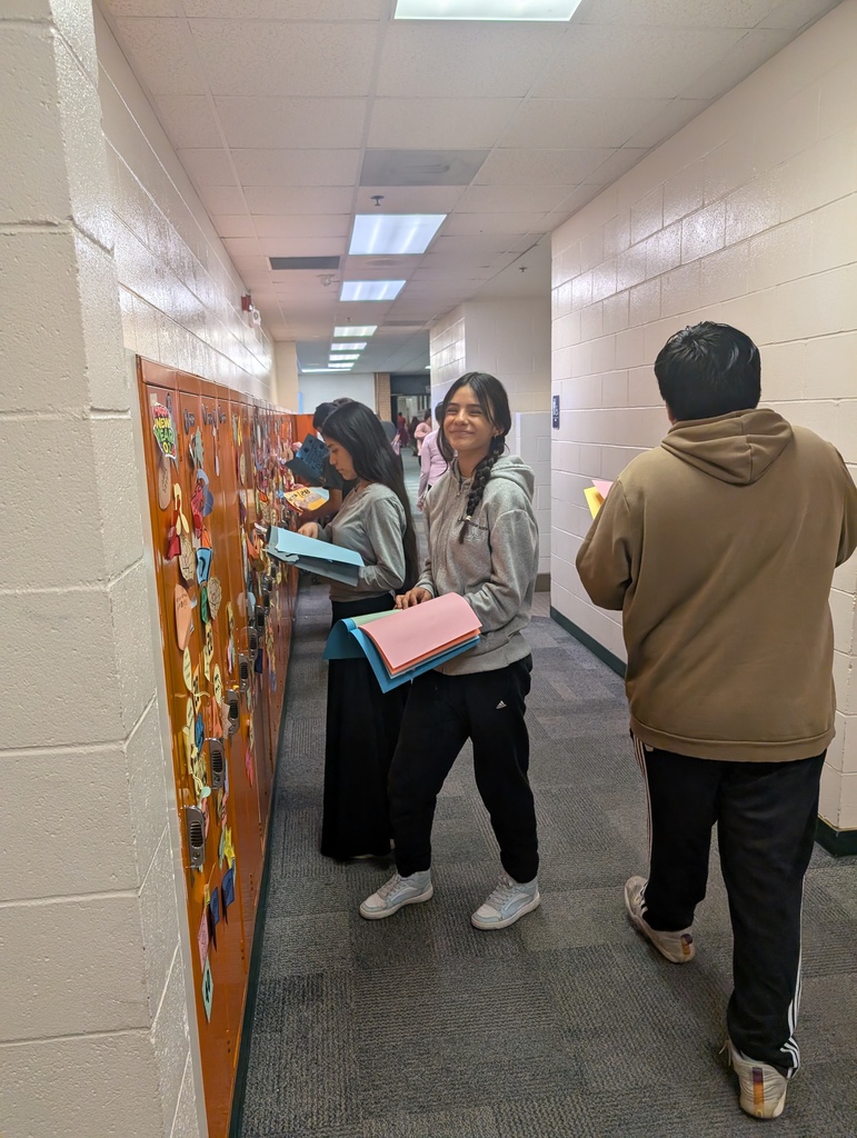 Student taking locker swag off of their lockers and putting it in their memory books.