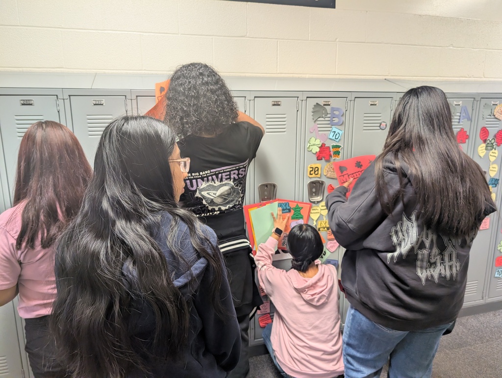 Student taking locker swag off of their lockers and putting it in their memory books.