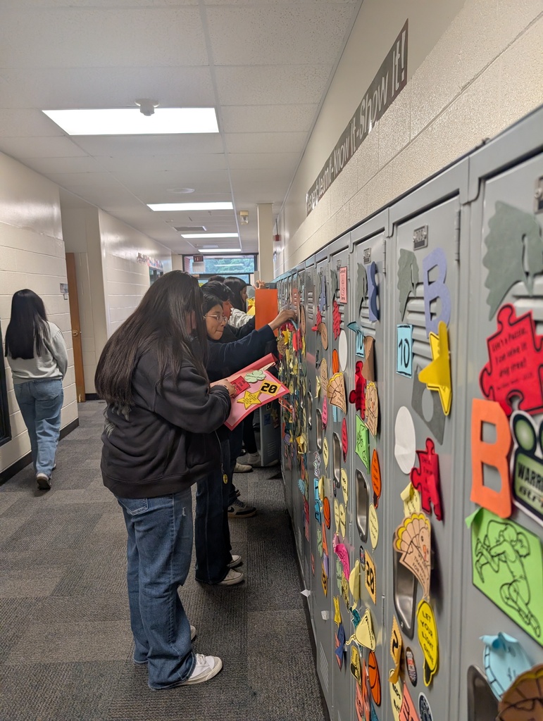 Student taking locker swag off of their lockers and putting it in their memory books.