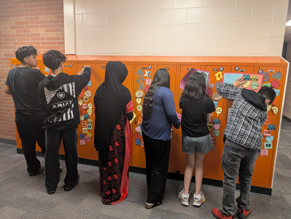 Student taking locker swag off of their lockers and putting it in their memory books.