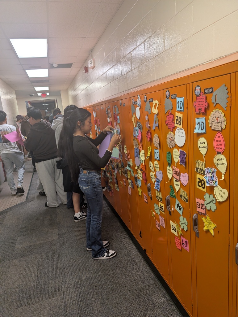 Student taking locker swag off of their lockers and putting it in their memory books.