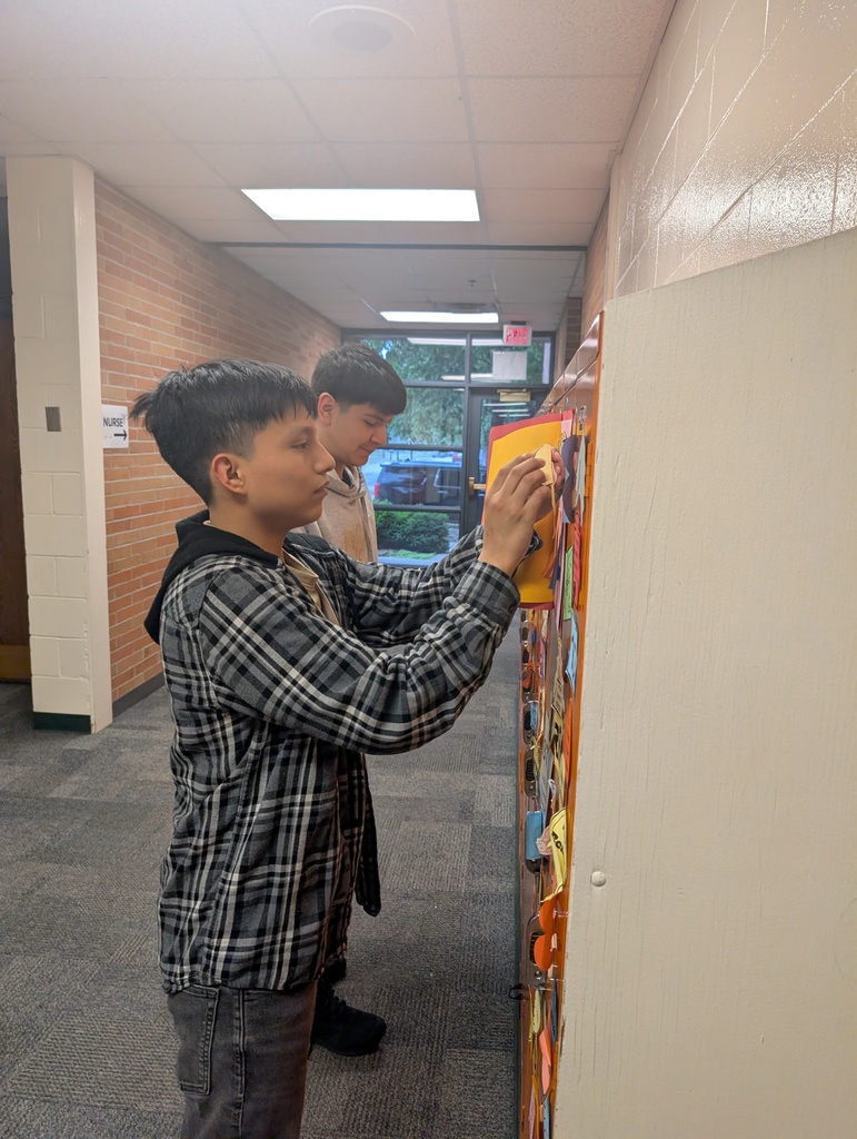 Student taking locker swag off of their lockers and putting it in their memory books.