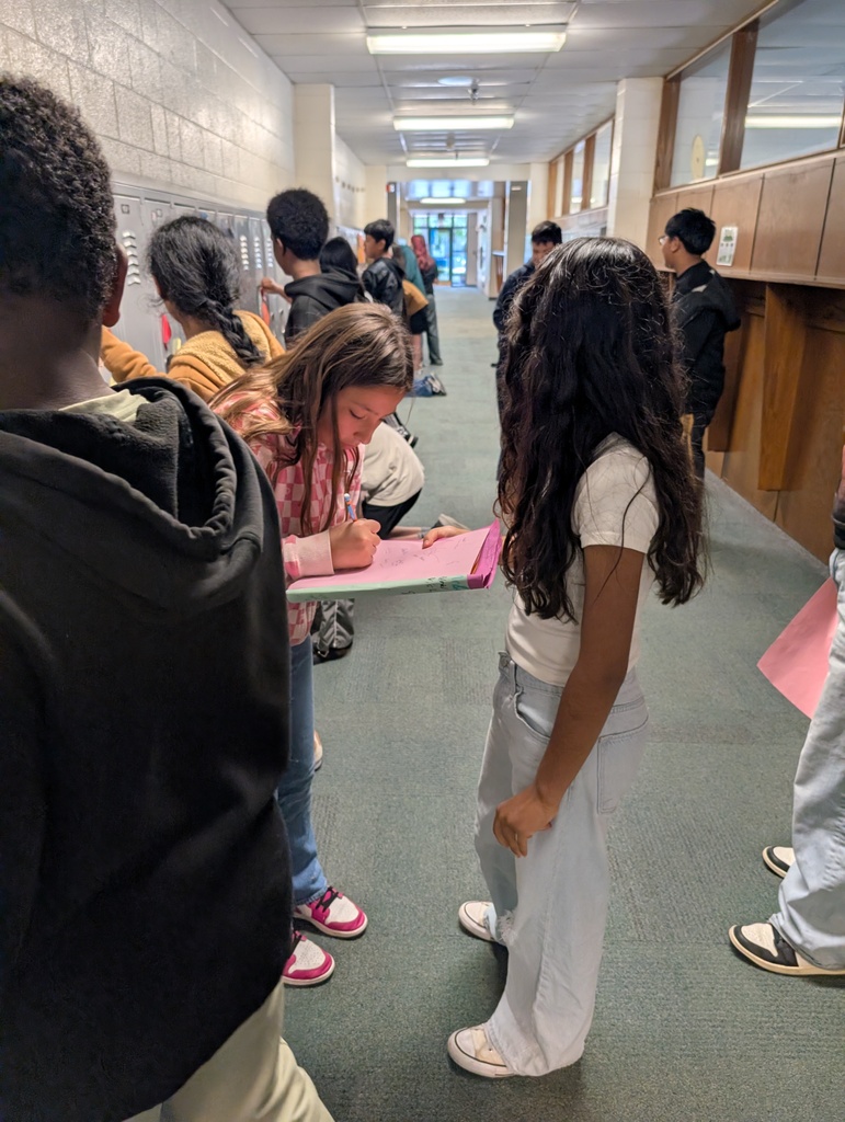 Student taking locker swag off of their lockers and putting it in their memory books.