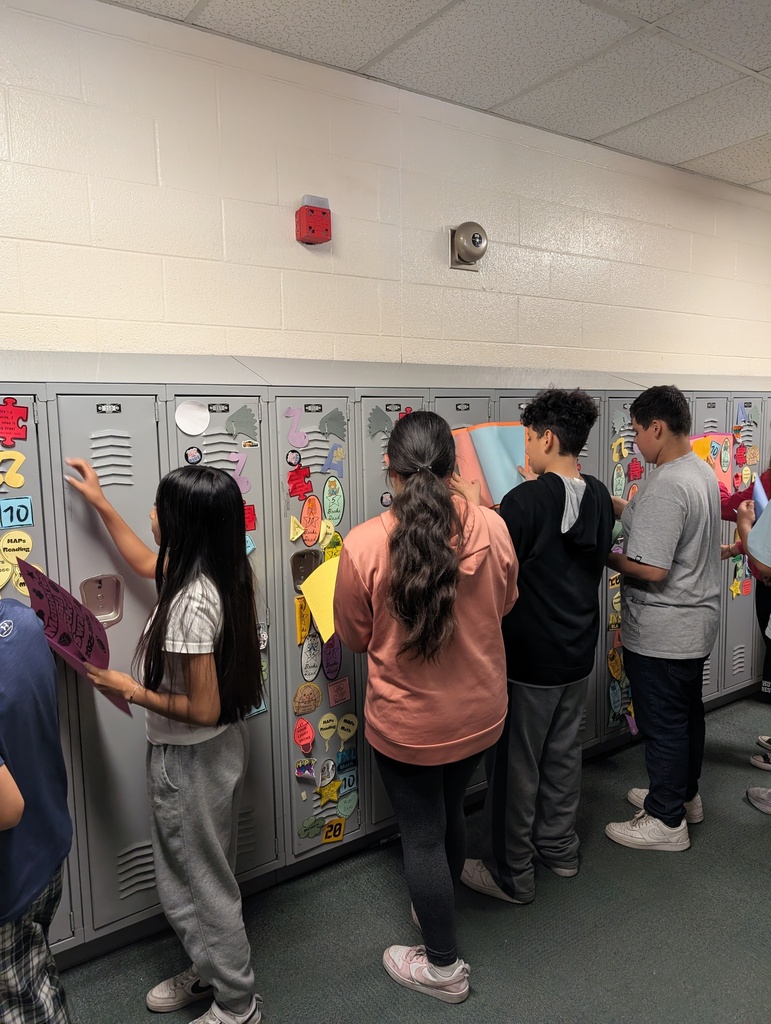 Student taking locker swag off of their lockers and putting it in their memory books.