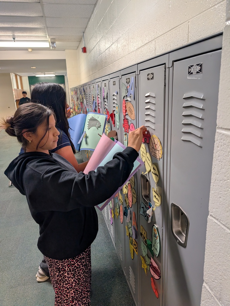 Student taking locker swag off of their lockers and putting it in their memory books.