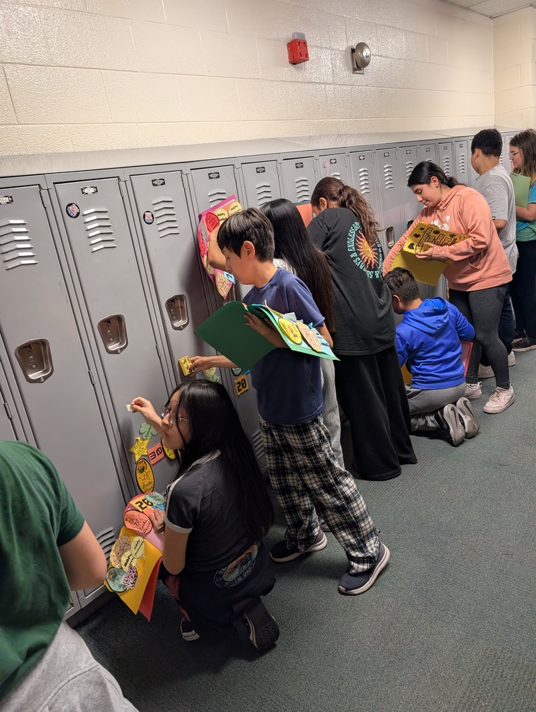 Student taking locker swag off of their lockers and putting it in their memory books.