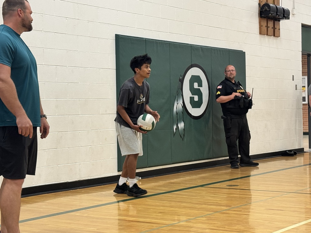 student serving the volleyball during staff vs. student volleyball game