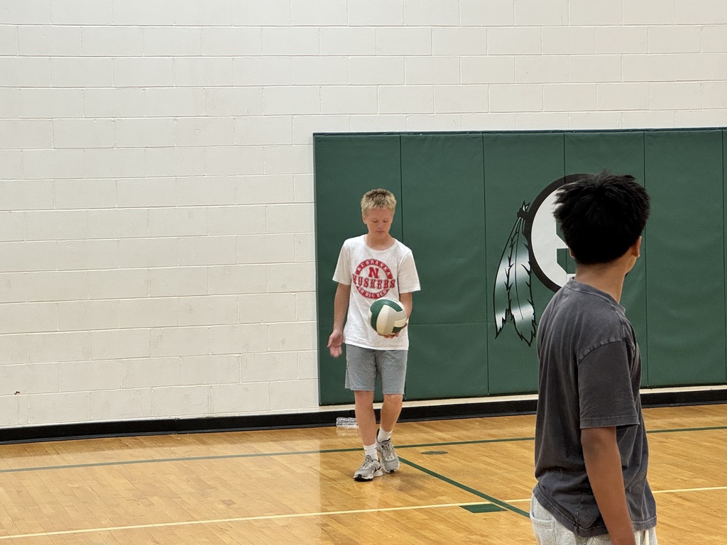 student serving the volleyball during staff vs. student volleyball game