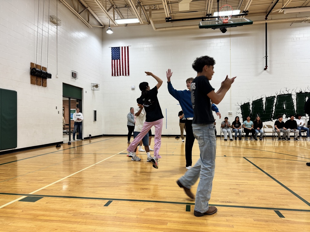 2 students high fiving during staff vs. student volleyball game