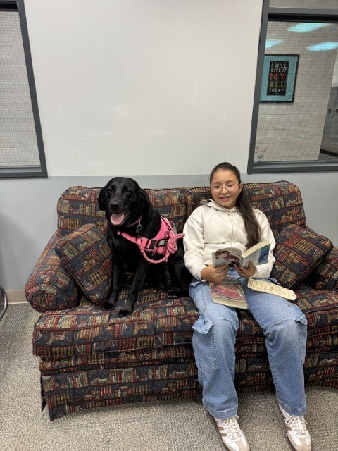 Student with Bugsy the dog reading a book