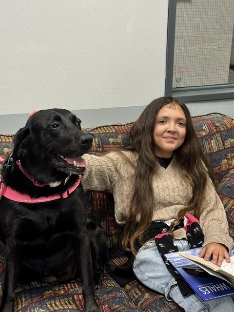 Student with Bugsy the dog reading a book