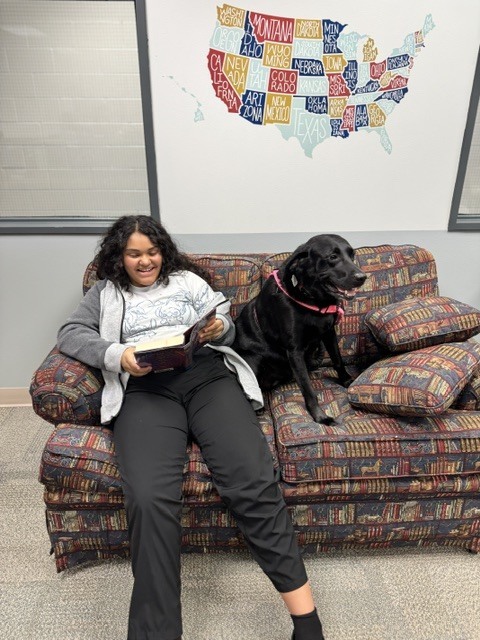 Student with Bugsy the dog reading a book