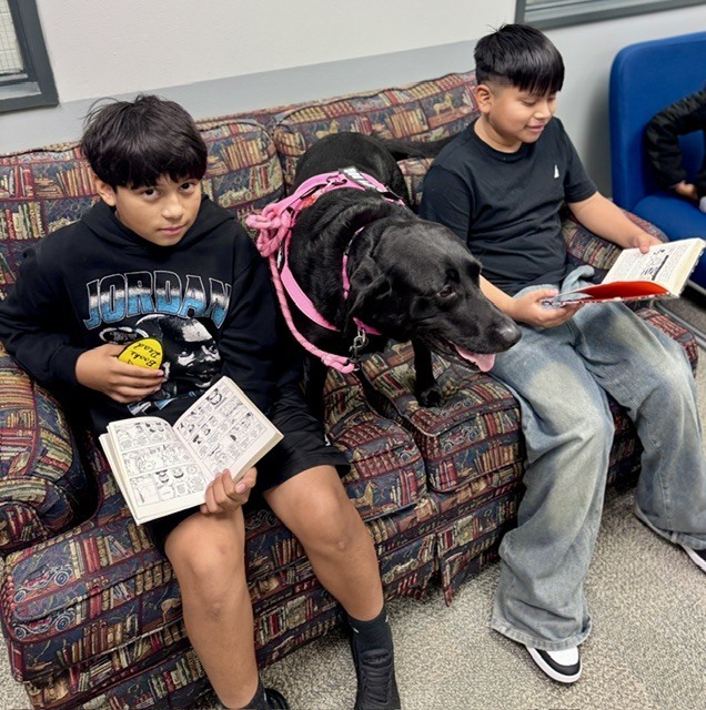 Students with Bugsy the dog reading a book