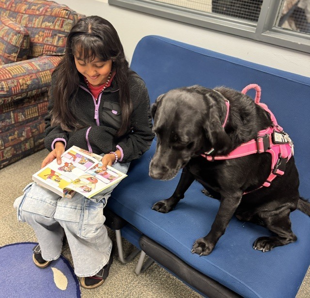 Student with Bugsy the dog reading a book