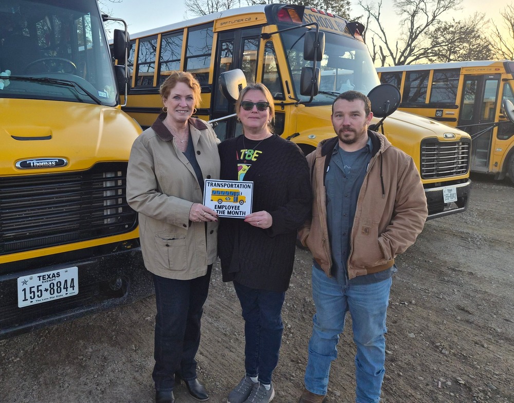 superintendent awarding bus driver with employee of the month. standing next to transportation supervisor