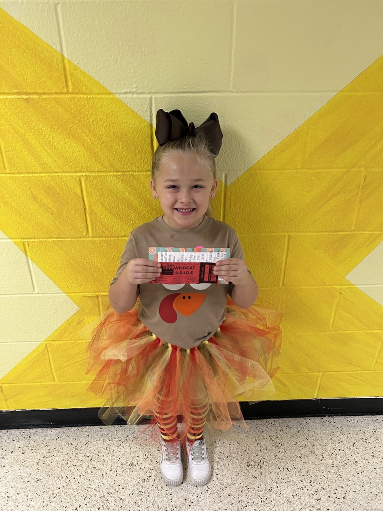 Smiling girl wearing a turkey costume and standing in front of a yellow backdrop