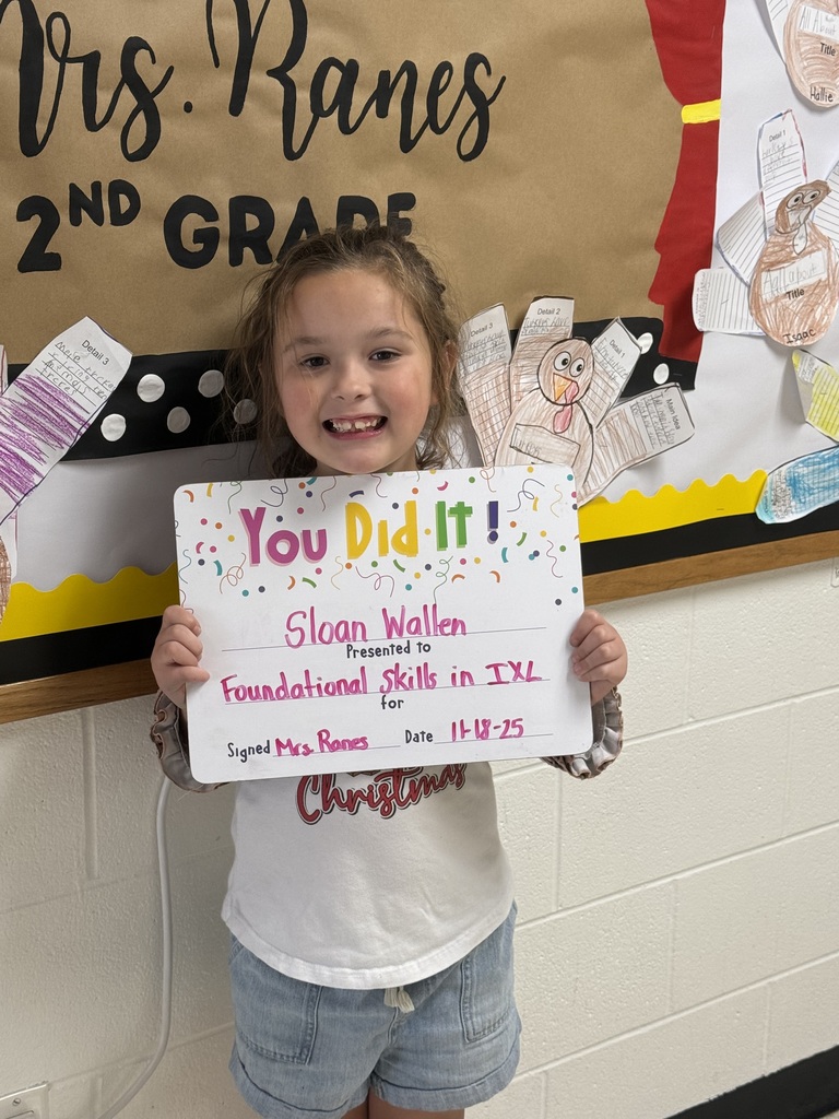 Child smiling, holding a sign telling of her accopmplishments