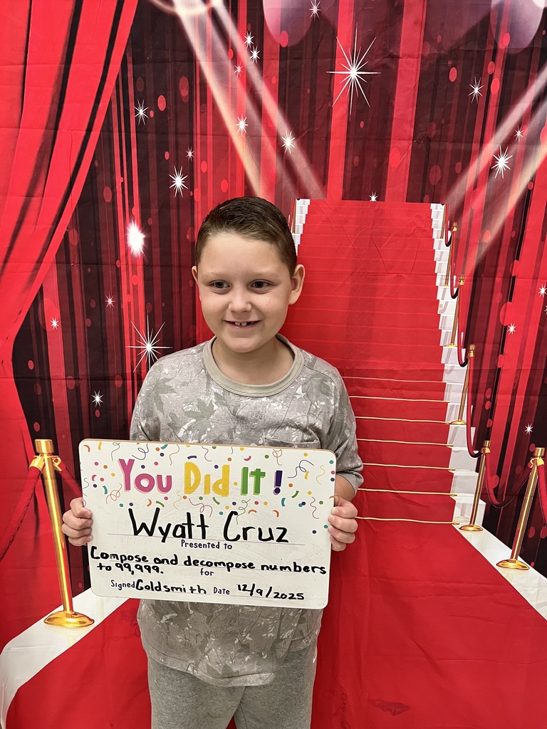 smiling boy holding a whiteboard, standing in front of a red background