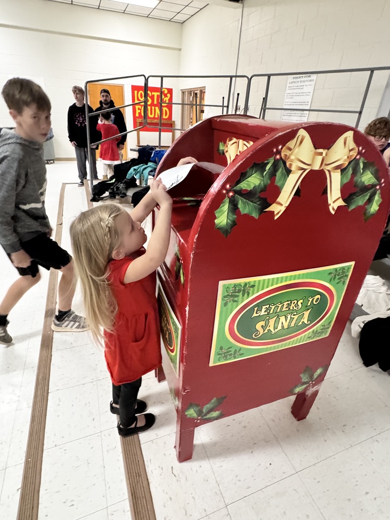 young girl putting a letter in a mailbox for Santa