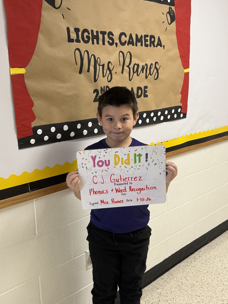 boy holding signboard, standing in front of a bulletin board