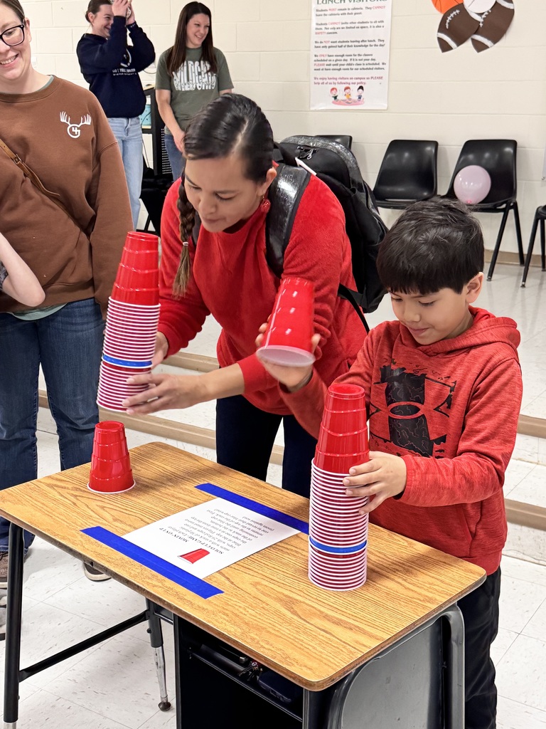 adult female and male child playing a game of stacking red plastic cups
