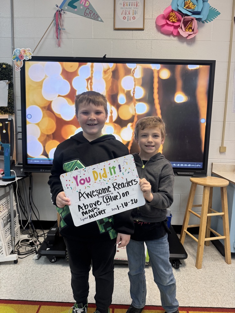 2 smiling boys holding a sign