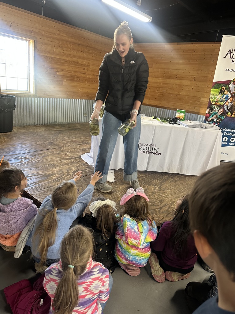 adult presenter showing students homemade canned pickels
