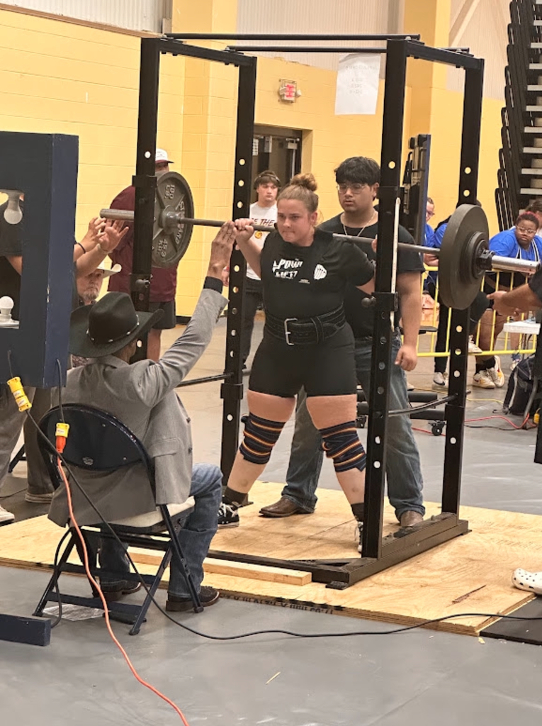 girl lifting barbell with weights with man judging her and a teenage boy spotting her