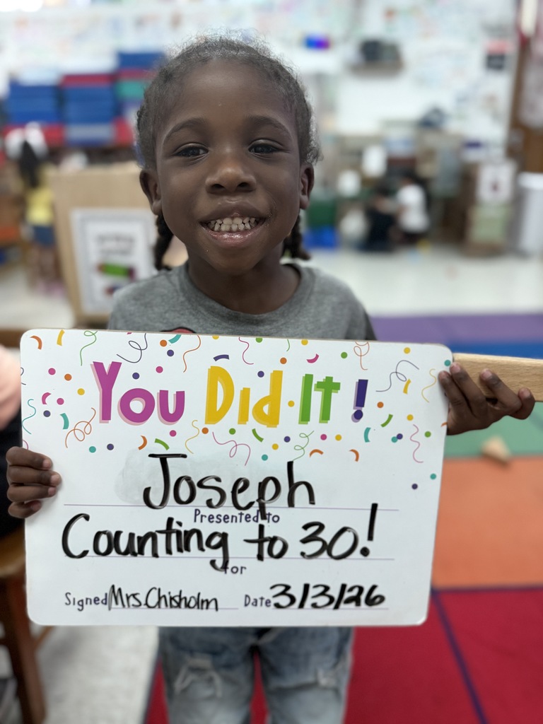 smiling child holding a celebration board