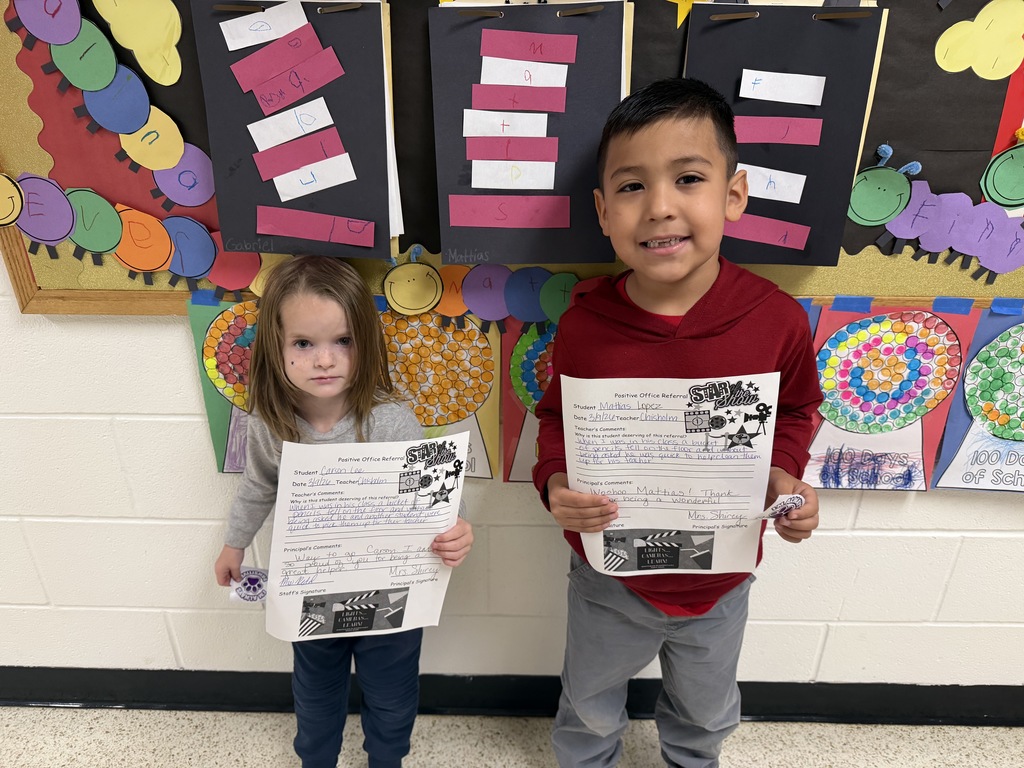 smiling children, each holding a piece of paper