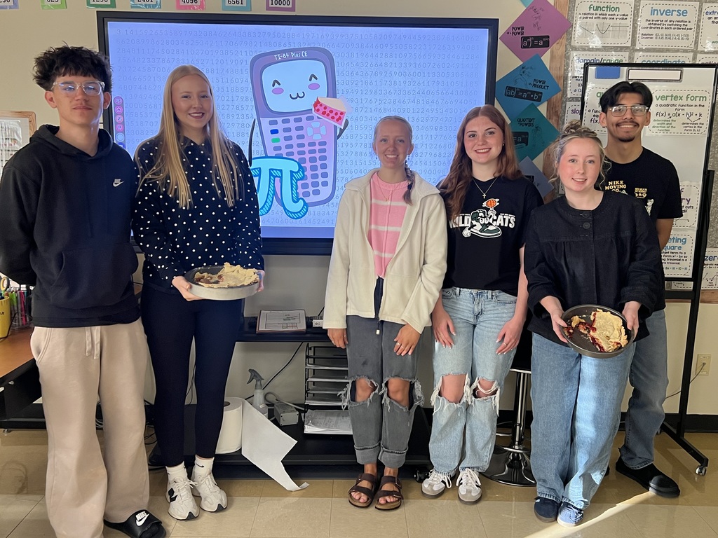 six students standing in front of a tc screen with an image of a calculator on it