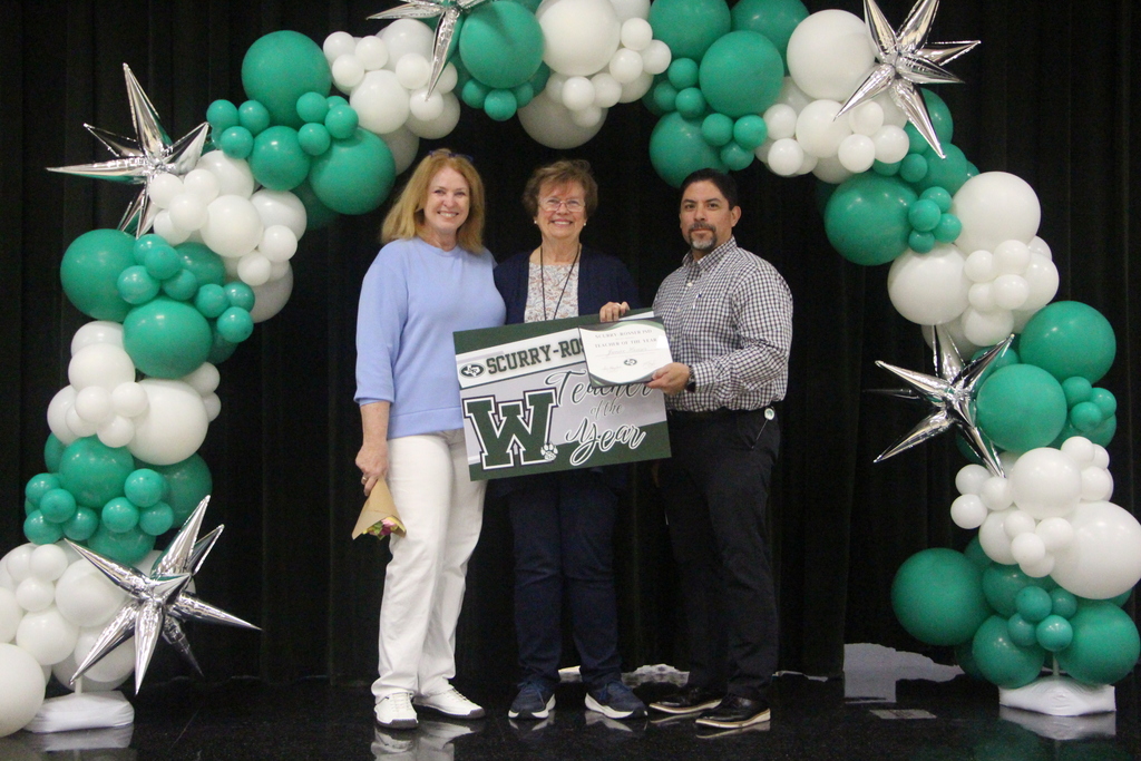 picture of two women and one man standing under a green and white balloon arch